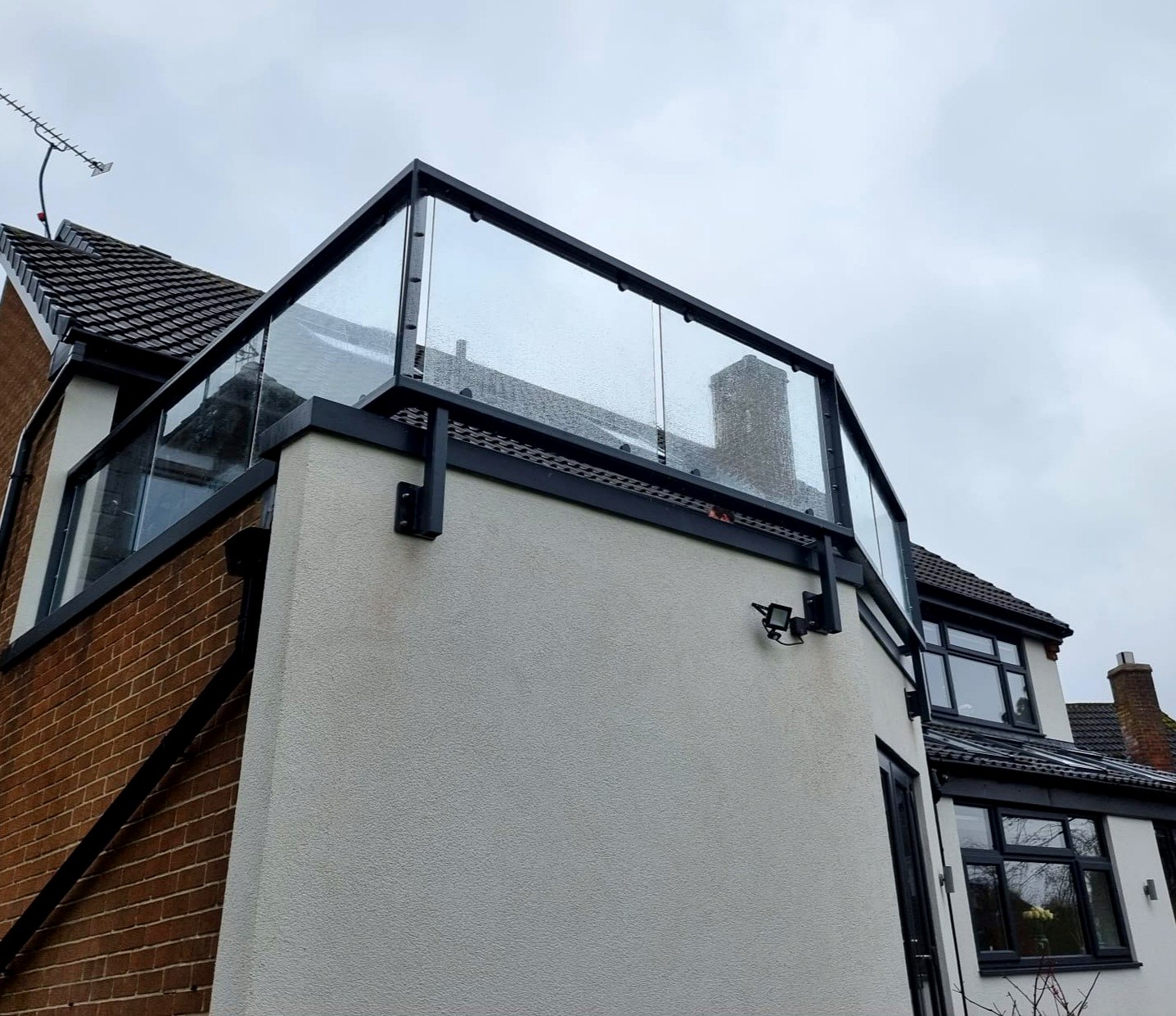 Glass balcony balustrade on a flat-roof parapet with anthracite grey steel rail, Norton, Sheffield